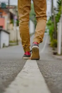 Image of man walking away. The shot is of his legs only.