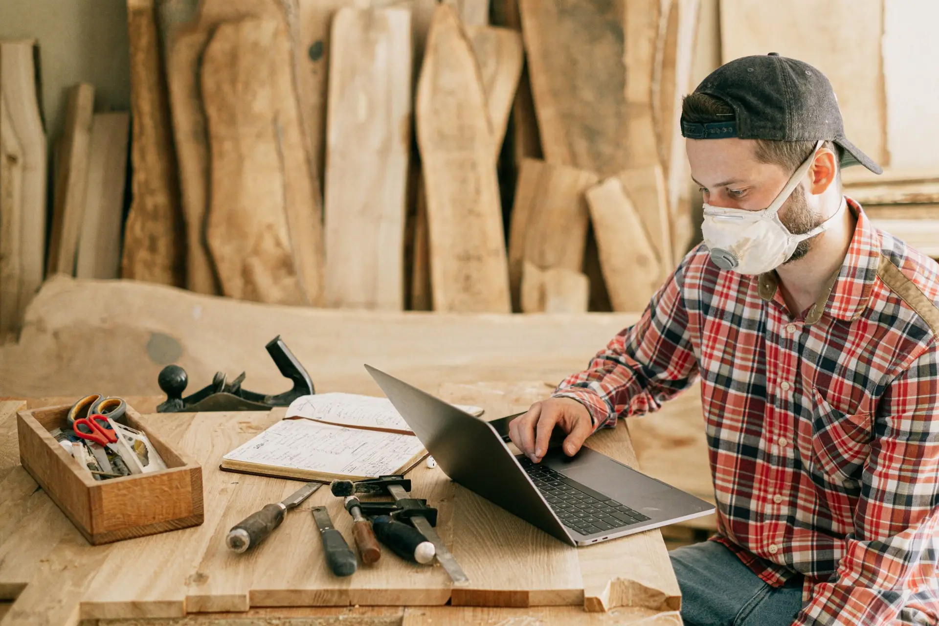 Woodworker sitting at table reviewing laptop computer