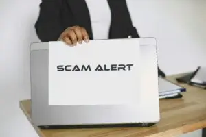 Image of laptop with a sign that says "Scam Alert"